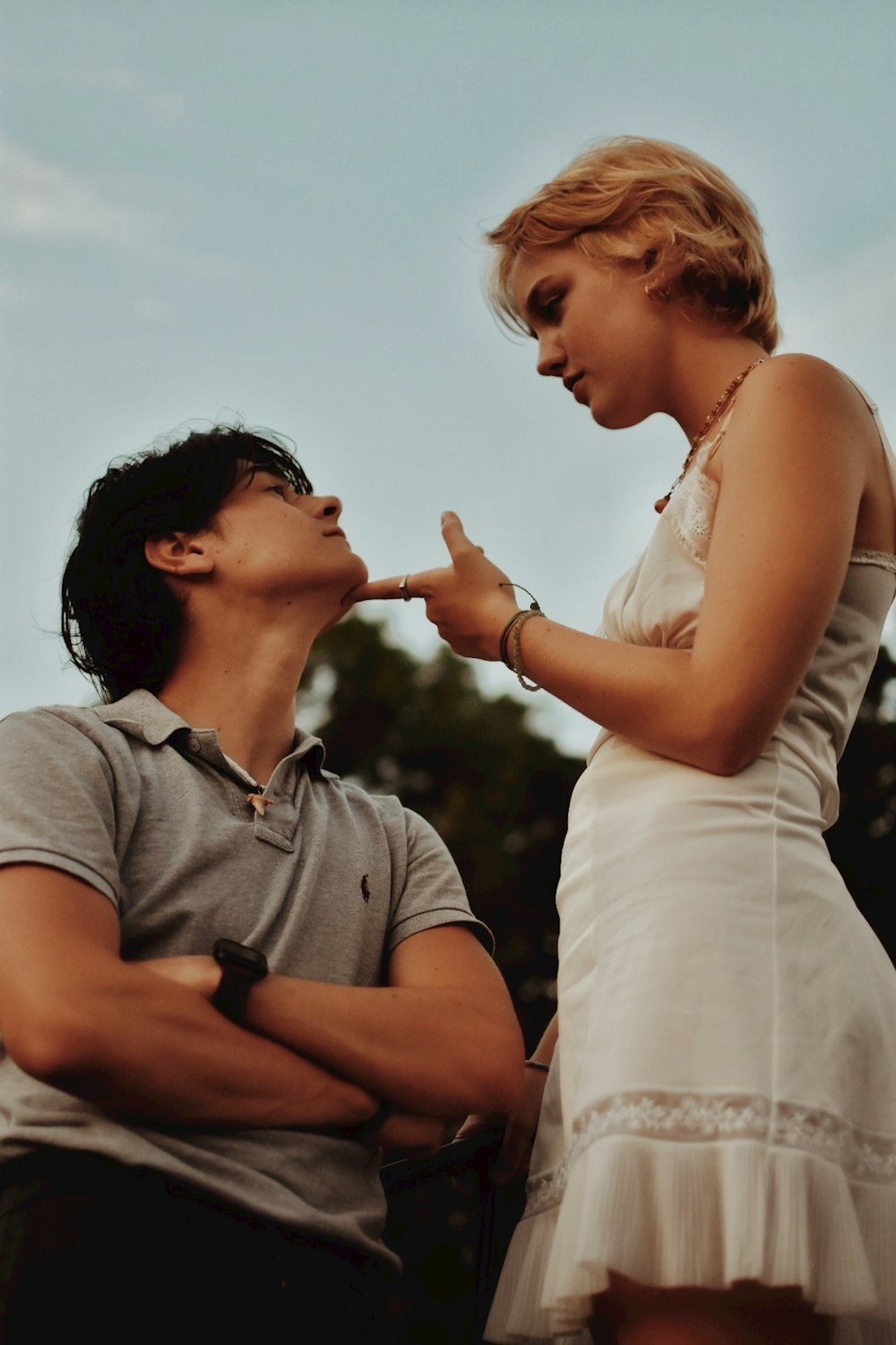 man in gray polo shirt kissing woman in white tank top during daytime