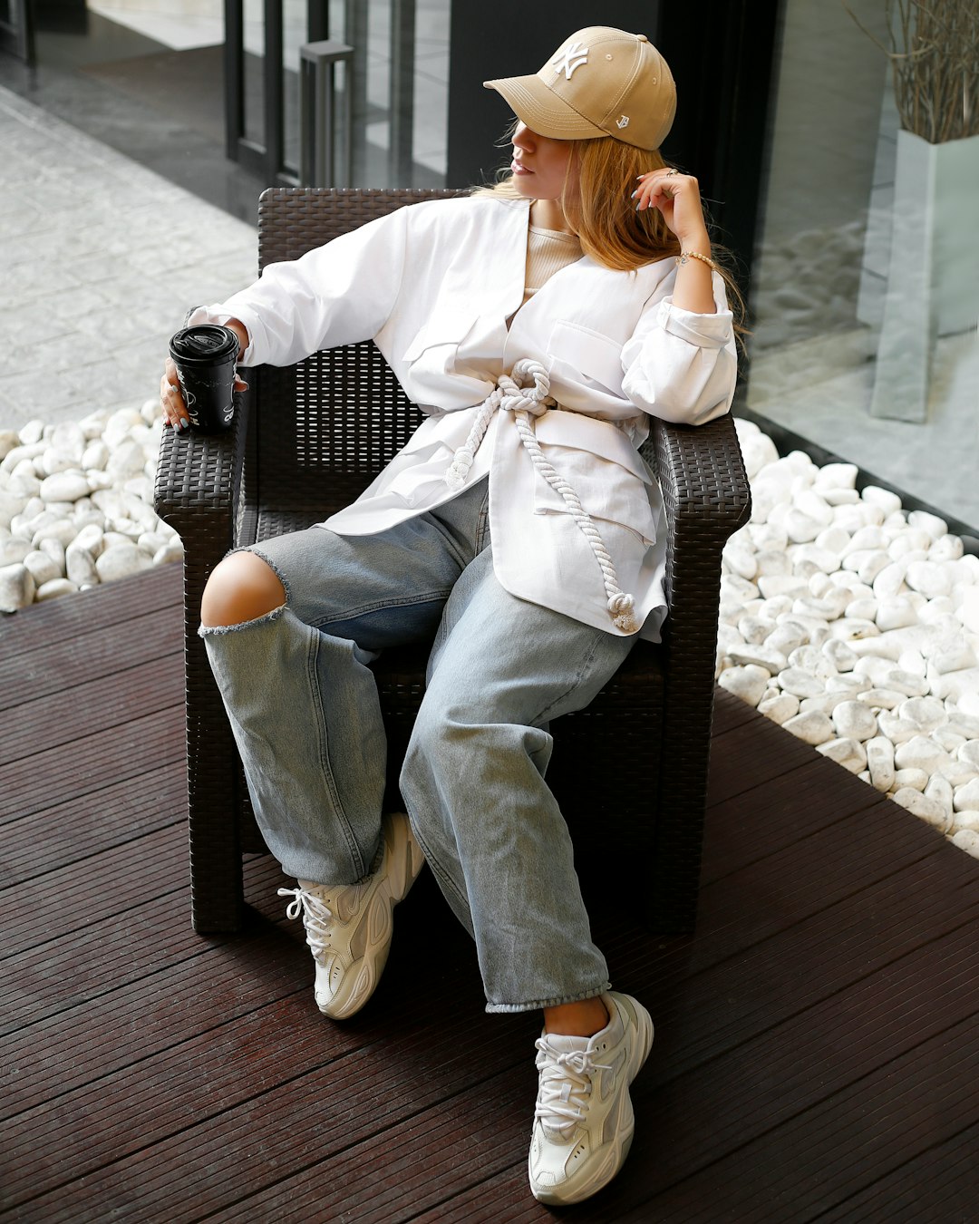 woman in white long sleeve shirt and blue denim jeans sitting on black wooden bench during
