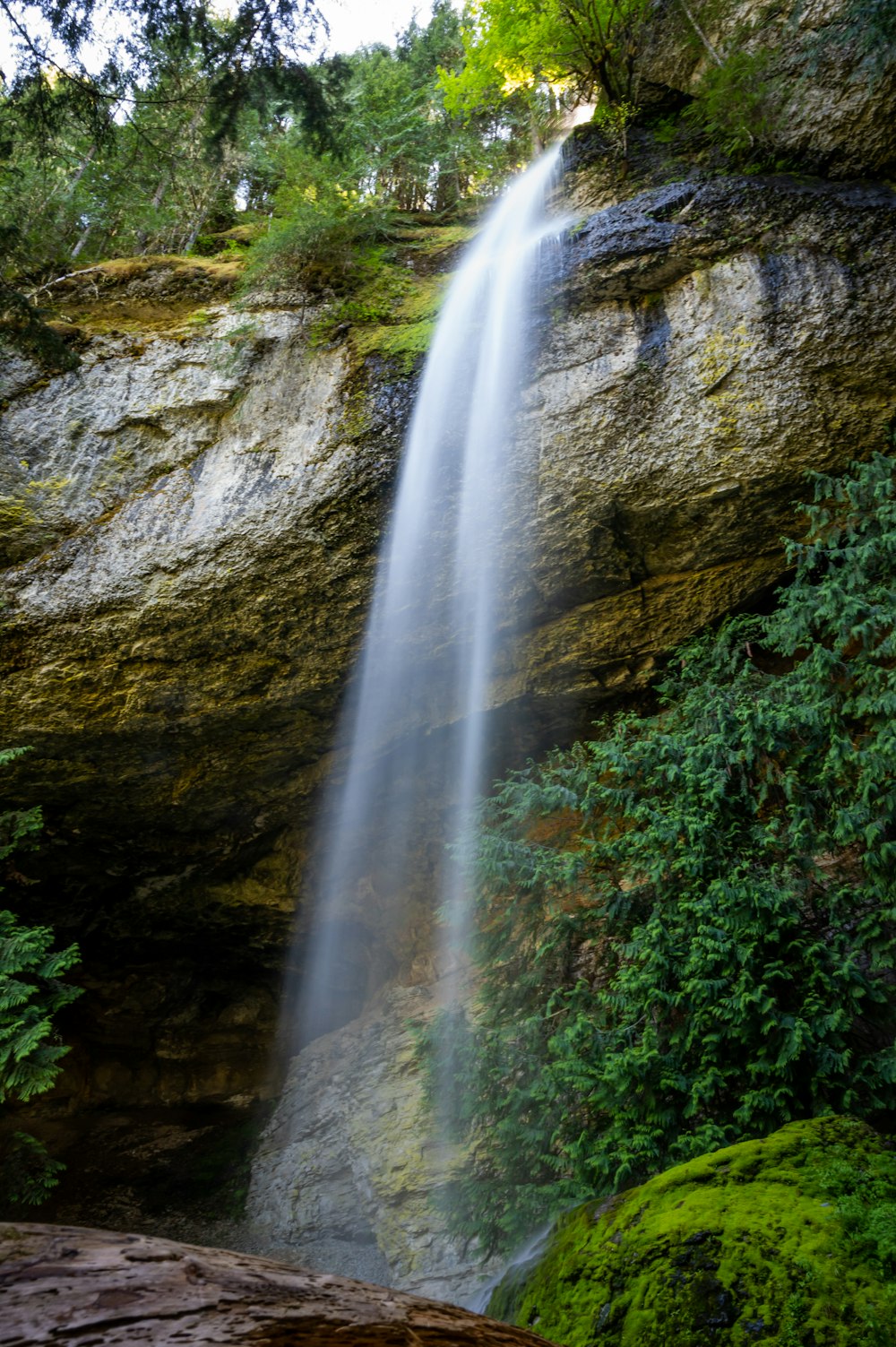 waterfalls in between green moss covered rocks
