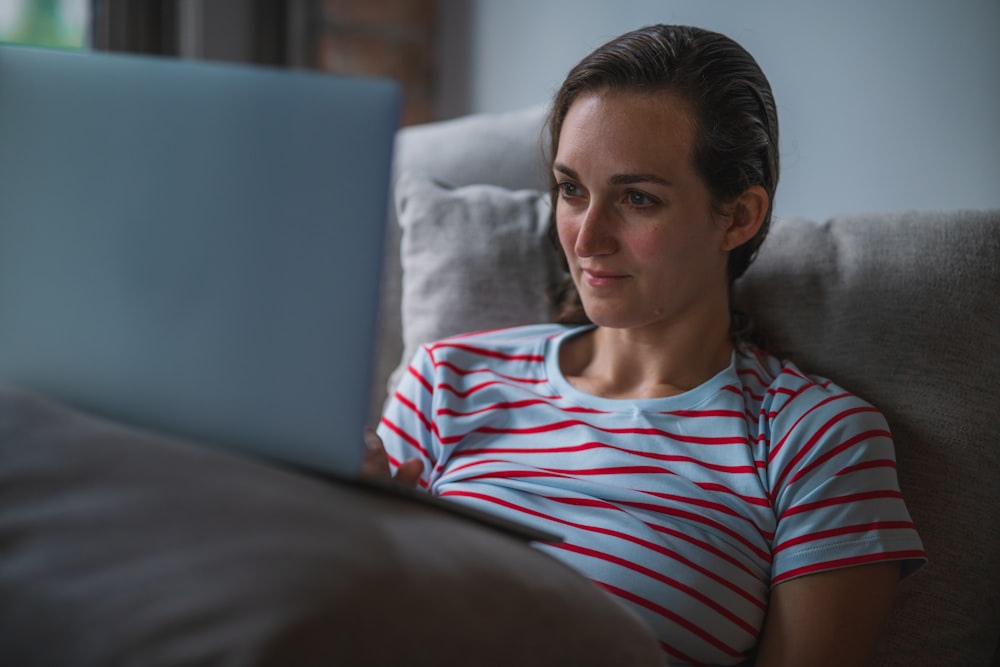 Mann in rot-weiß gestreiftem Rundhals-T-Shirt sitzt auf blauem Sofa