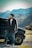 man in black jacket and blue denim jeans standing beside black car