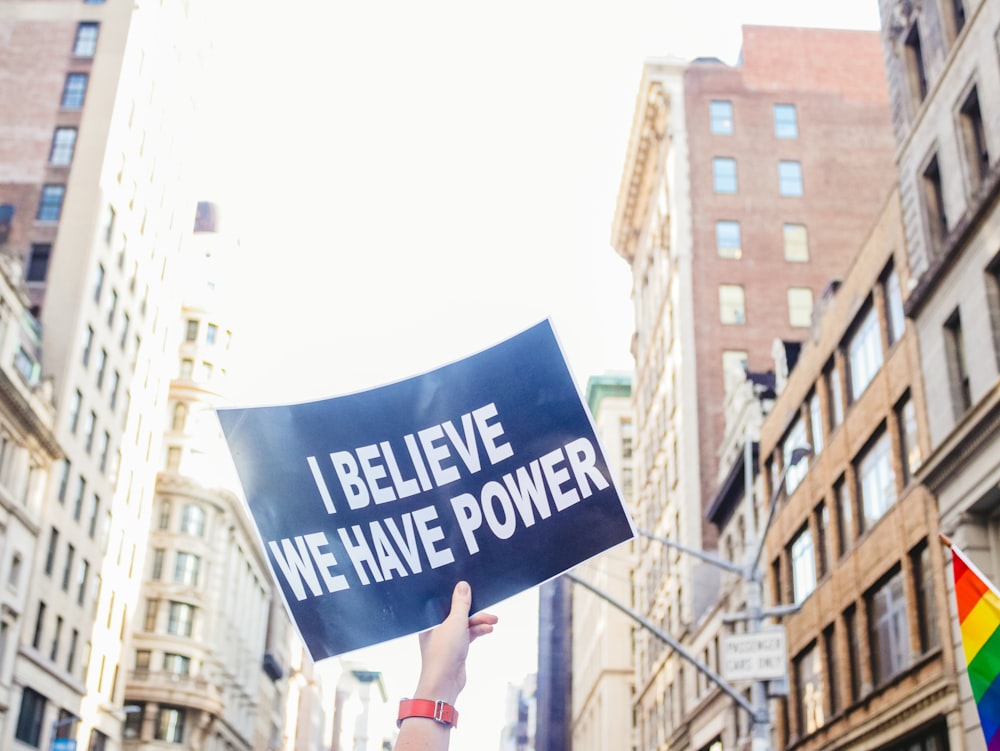a person holding a sign that says i believe we have power