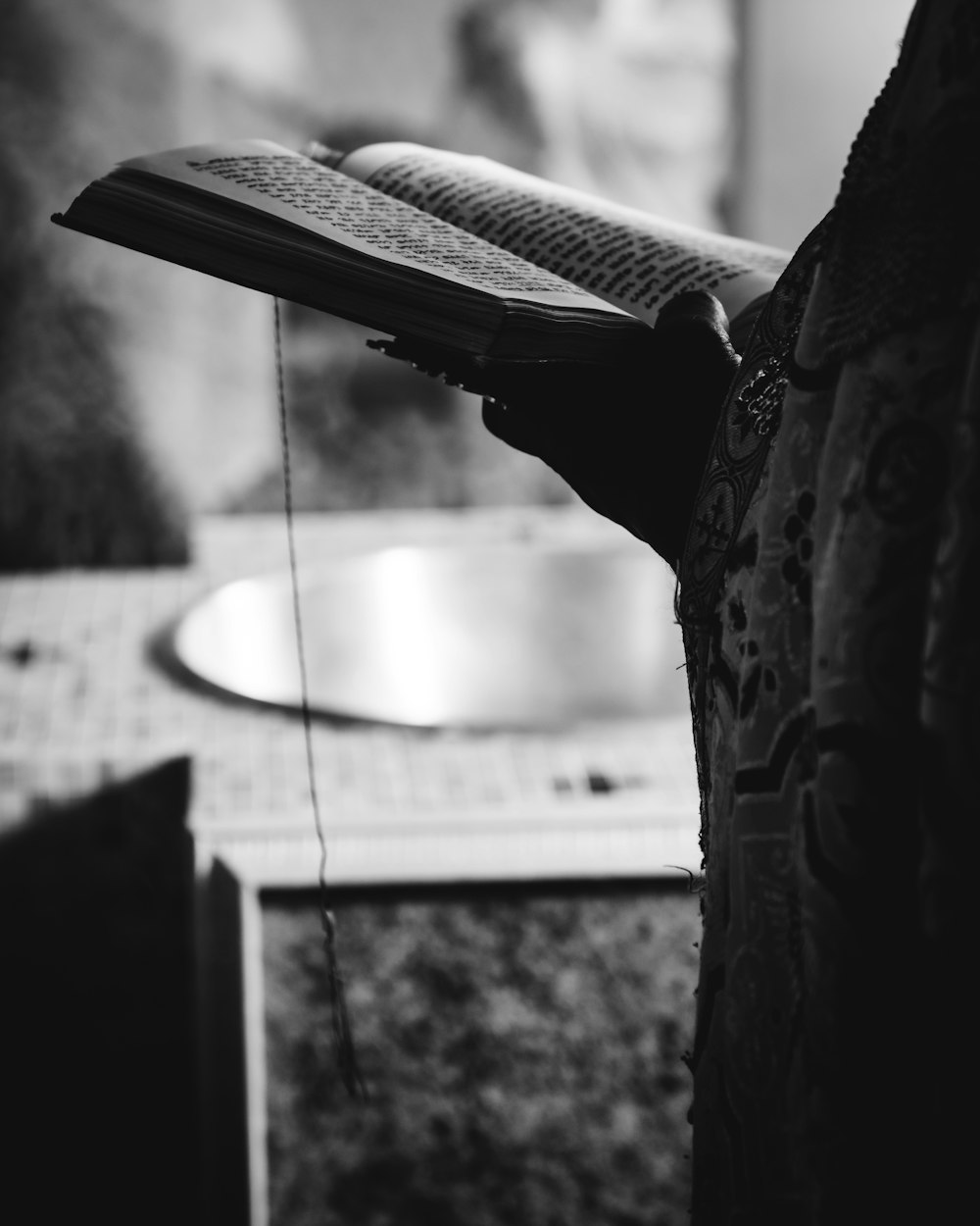 grayscale photo of person holding book