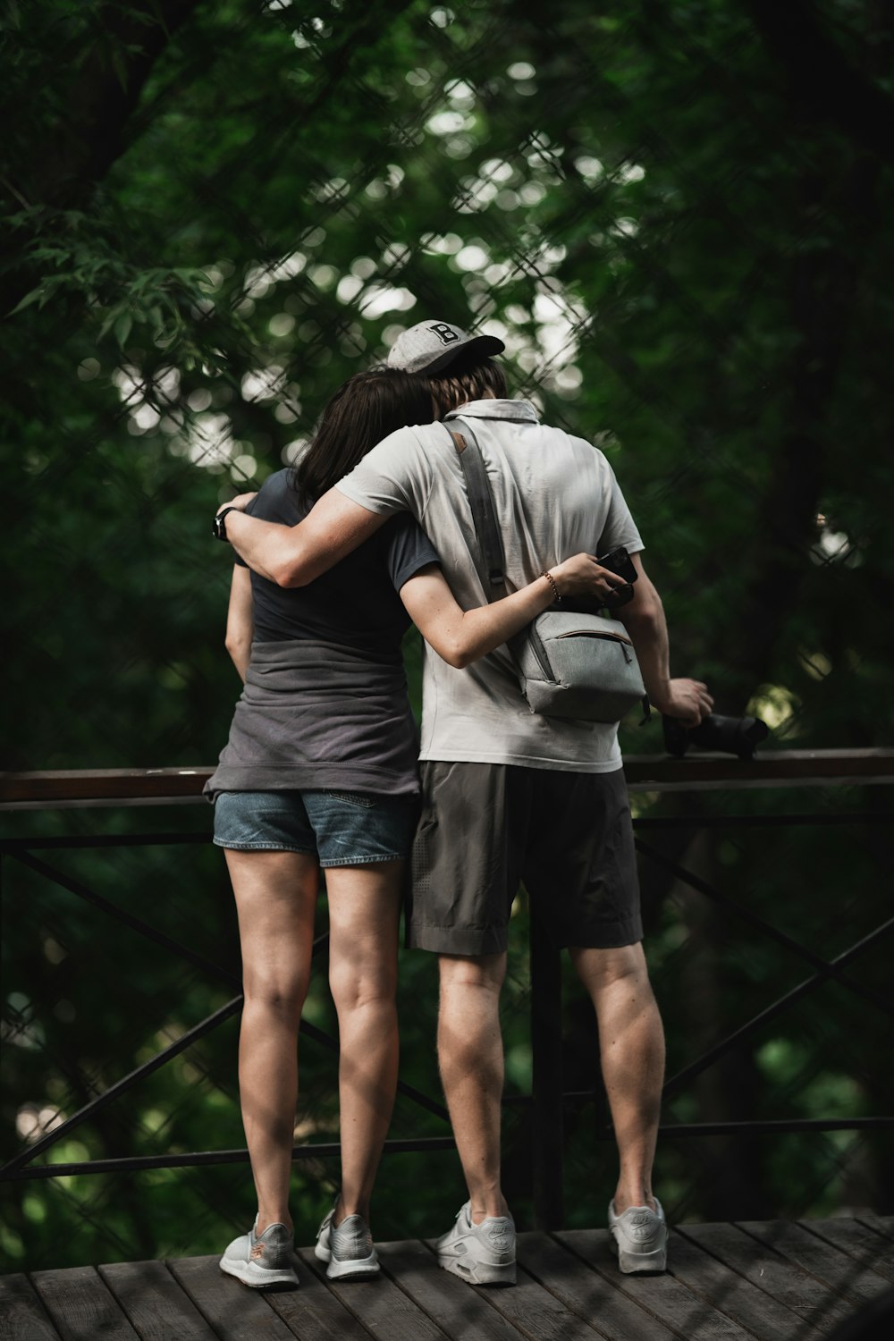 man in grey t-shirt and black shorts standing on bridge