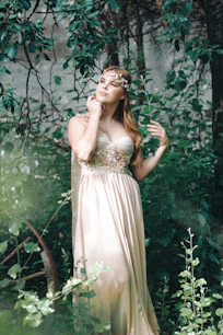 woman in white floral dress standing beside green plant