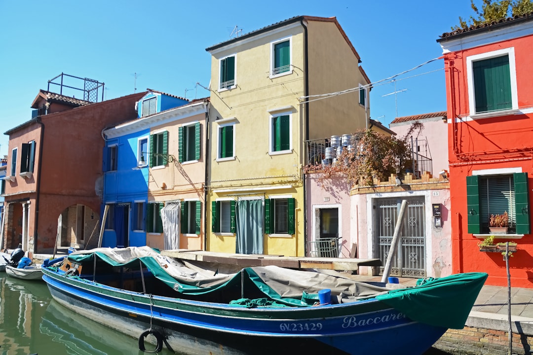 blue and white boat on dock near brown concrete building during daytime