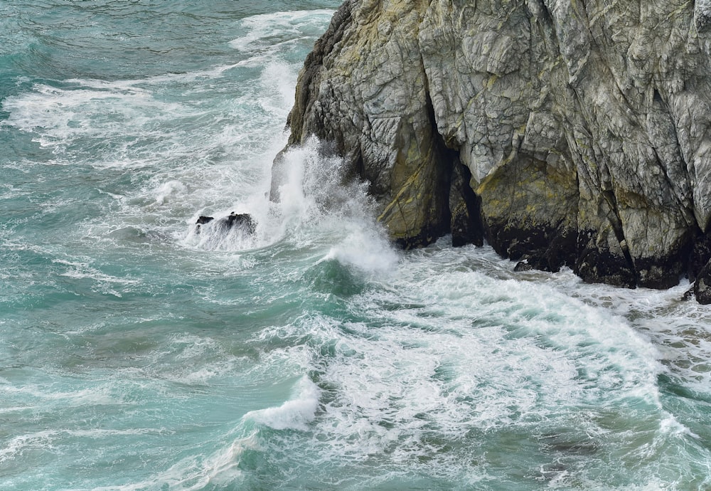 sea waves crashing on rocky shore during daytime