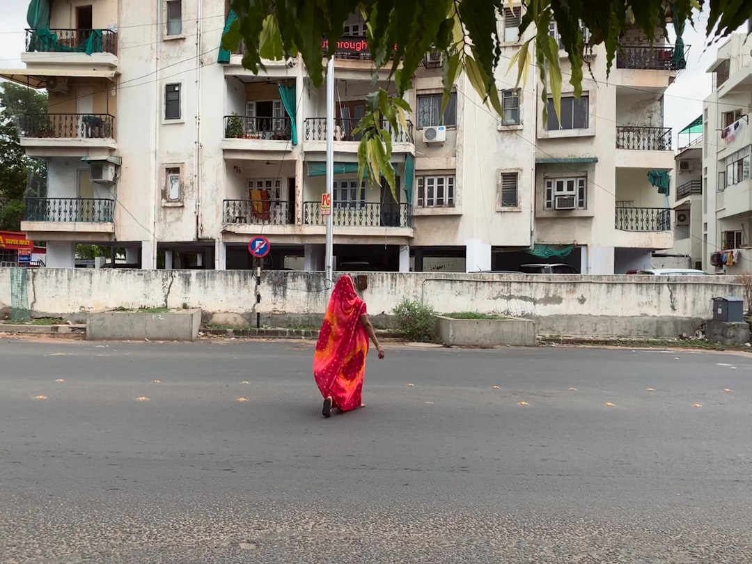 woman in red dress walking on street during daytime