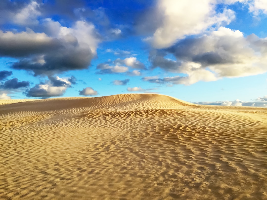 brown sand under blue sky and white clouds during daytime