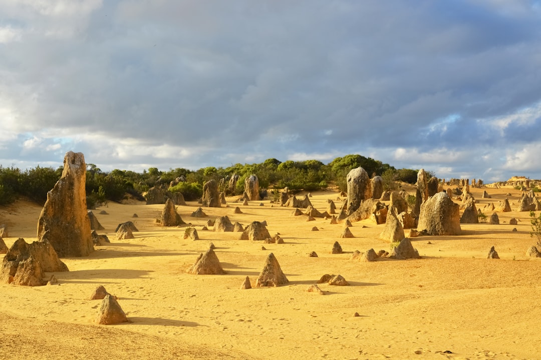 brown rocks on brown sand under white clouds during daytime