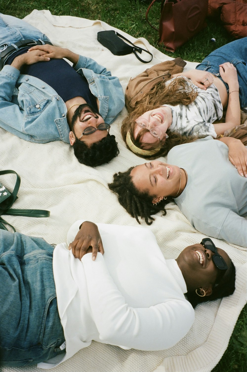 Group of people laughing while laying on grass