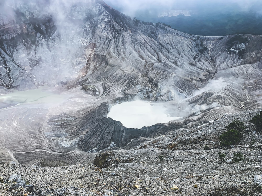 gray rocky mountain with white smoke during daytime