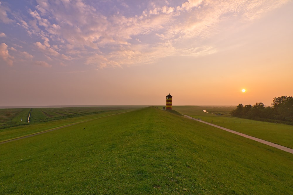 brown and black lighthouse on green grass field under blue sky during daytime