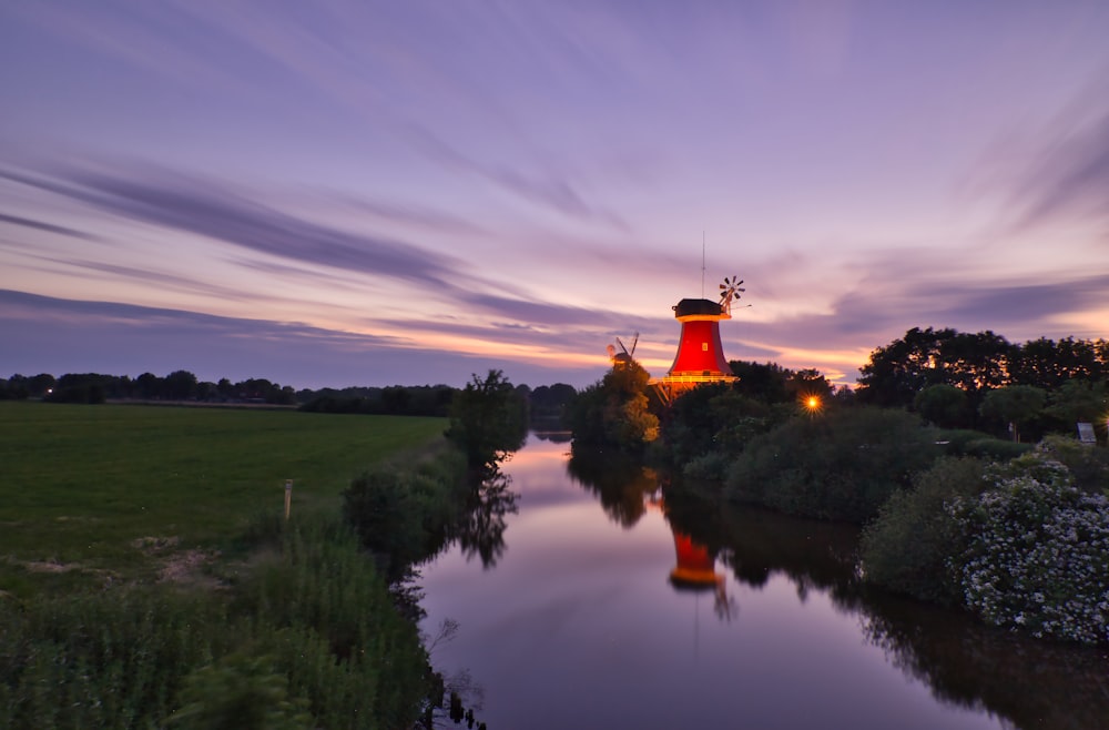 orange and white lighthouse near green trees under cloudy sky during daytime