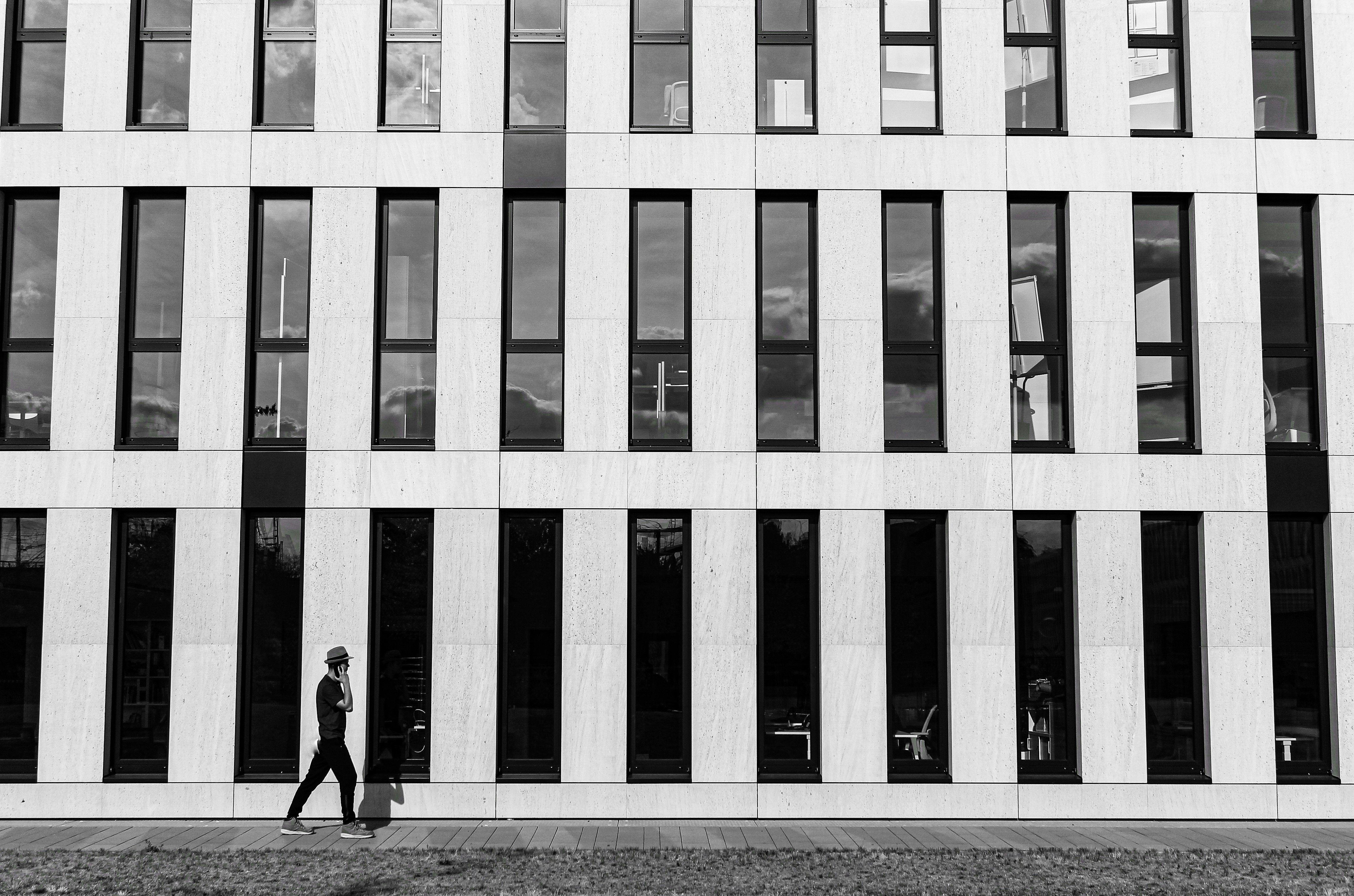 man in black jacket walking on sidewalk near building during daytime