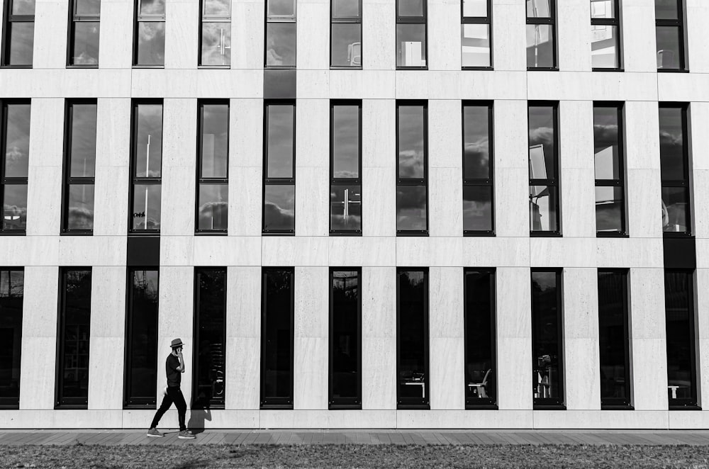 man in black jacket walking on sidewalk near building during daytime