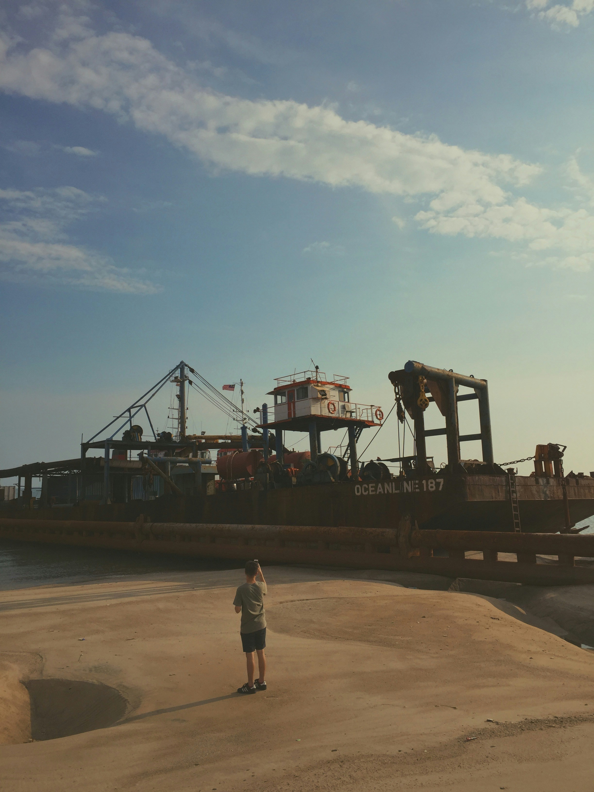 man in white shirt standing near black ship during daytime