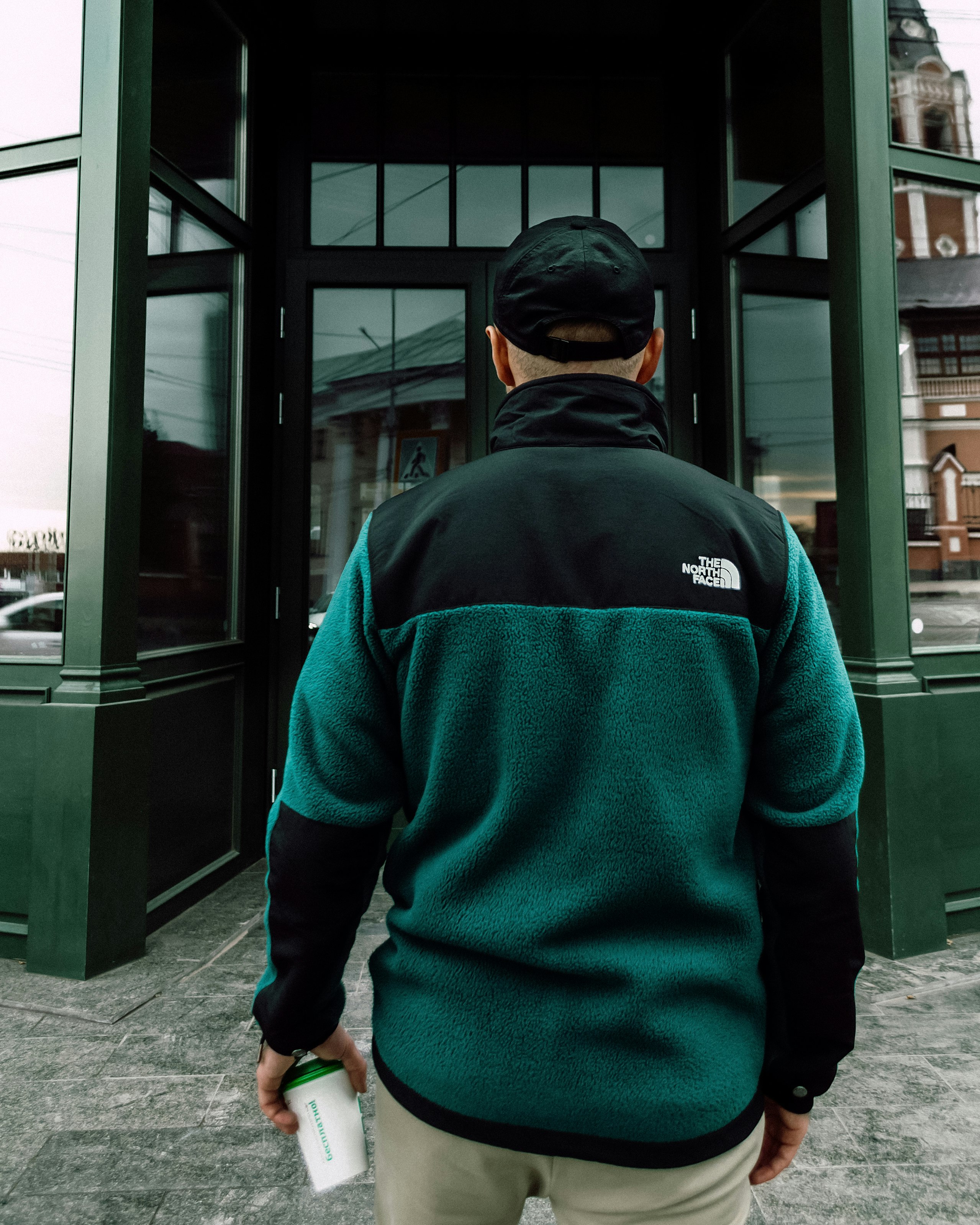 man in blue and black hoodie standing near glass window