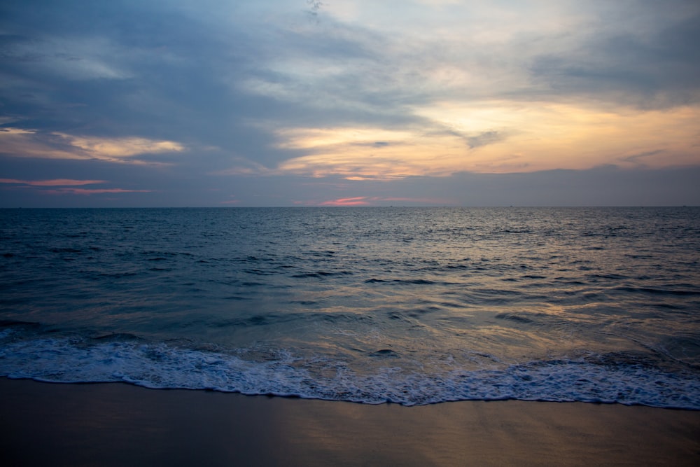 ocean waves crashing on shore during sunset