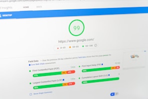 A computer screen displays a PageSpeed Insights report for the website google.com, showing a high performance score of 99. The report includes metrics such as First Contentful Paint (FCP), Largest Contentful Paint (LCP), First Input Delay (FID), and Cumulative Layout Shift (CLS), all of which are represented with graphical progress bars.