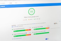 A computer screen displays a PageSpeed Insights report for the website google.com, showing a high performance score of 99. The report includes metrics such as First Contentful Paint (FCP), Largest Contentful Paint (LCP), First Input Delay (FID), and Cumulative Layout Shift (CLS), all of which are represented with graphical progress bars.