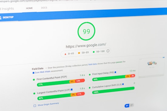 A computer screen displays a PageSpeed Insights report for the website google.com, showing a high performance score of 99. The report includes metrics such as First Contentful Paint (FCP), Largest Contentful Paint (LCP), First Input Delay (FID), and Cumulative Layout Shift (CLS), all of which are represented with graphical progress bars.