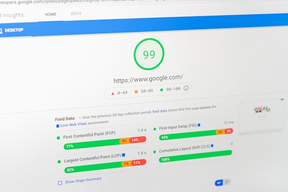 A computer screen displays a PageSpeed Insights report for the website google.com, showing a high performance score of 99. The report includes metrics such as First Contentful Paint (FCP), Largest Contentful Paint (LCP), First Input Delay (FID), and Cumulative Layout Shift (CLS), all of which are represented with graphical progress bars.