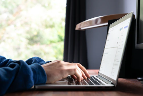 A friendly person typing on a laptop with rentiva interface on screen, sunlight filtering through window.