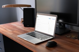 A modern office desk with a laptop showing a company profile website.