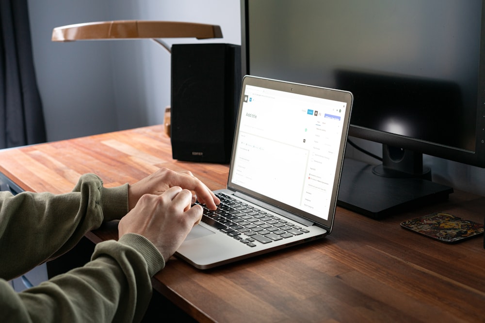 person in gray jacket using macbook pro