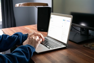 person using macbook pro on brown wooden table