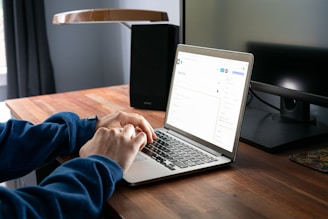 person using macbook pro on brown wooden table