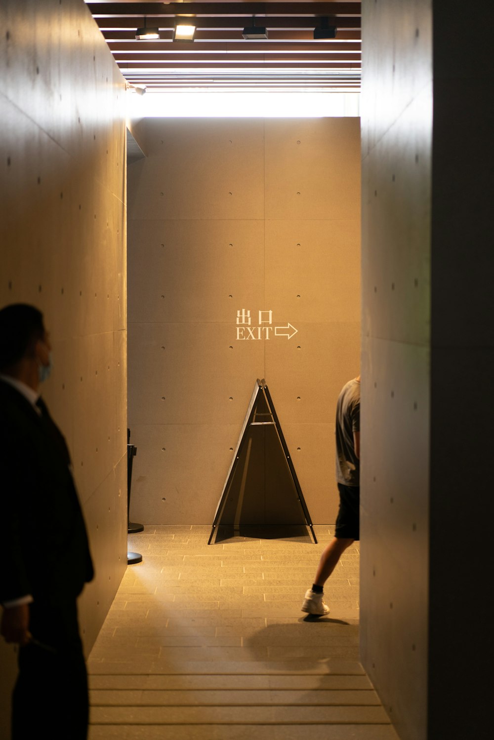 man in black coat walking on hallway