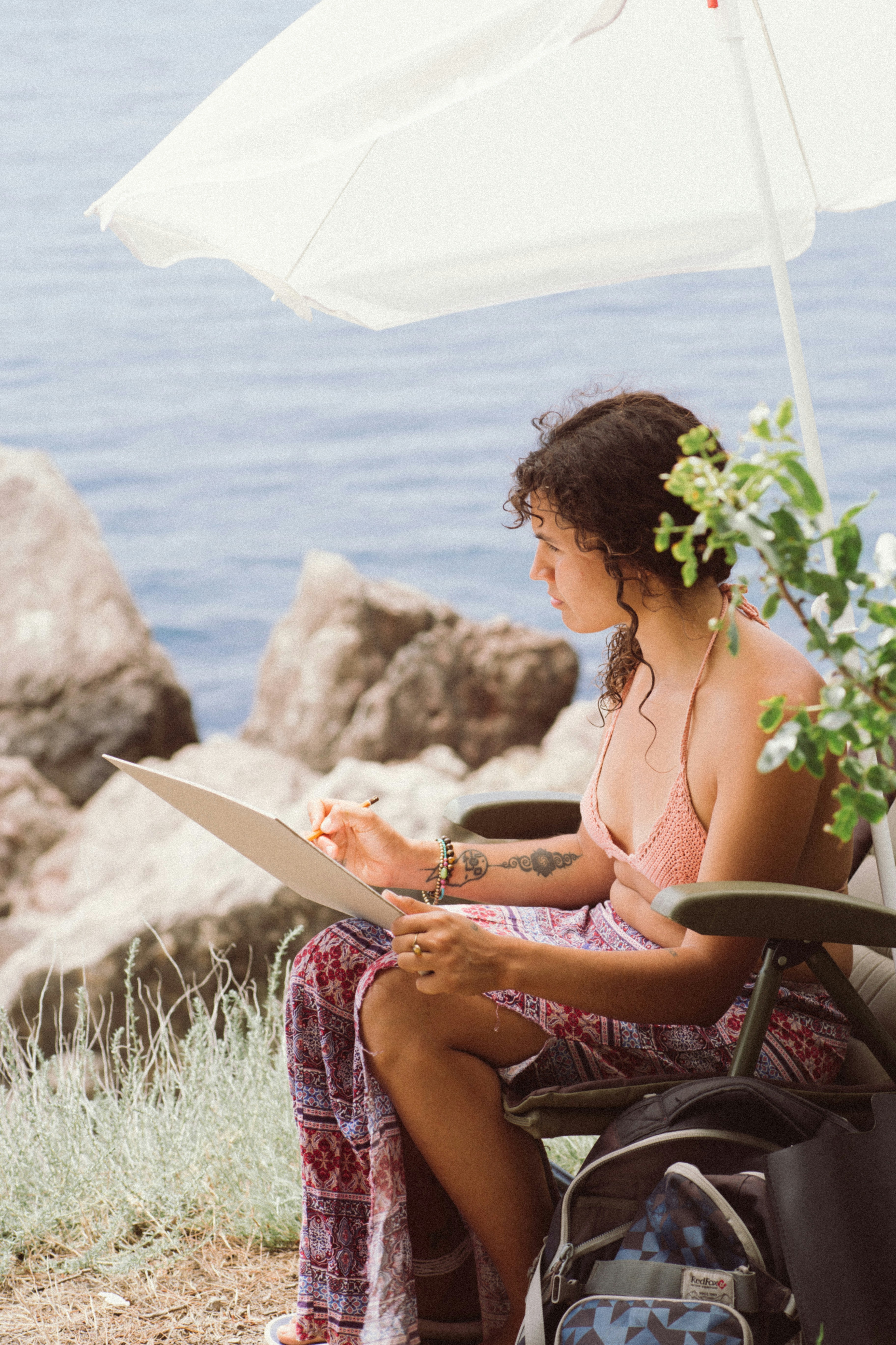 woman in purple and white floral dress sitting on black chair reading book