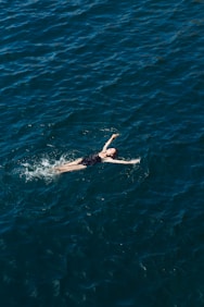 woman in black bikini swimming in blue water