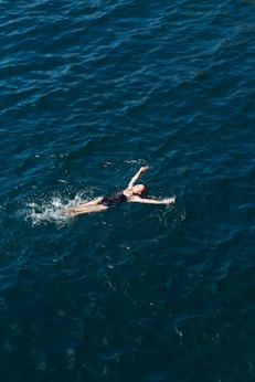 woman in black bikini swimming in blue water