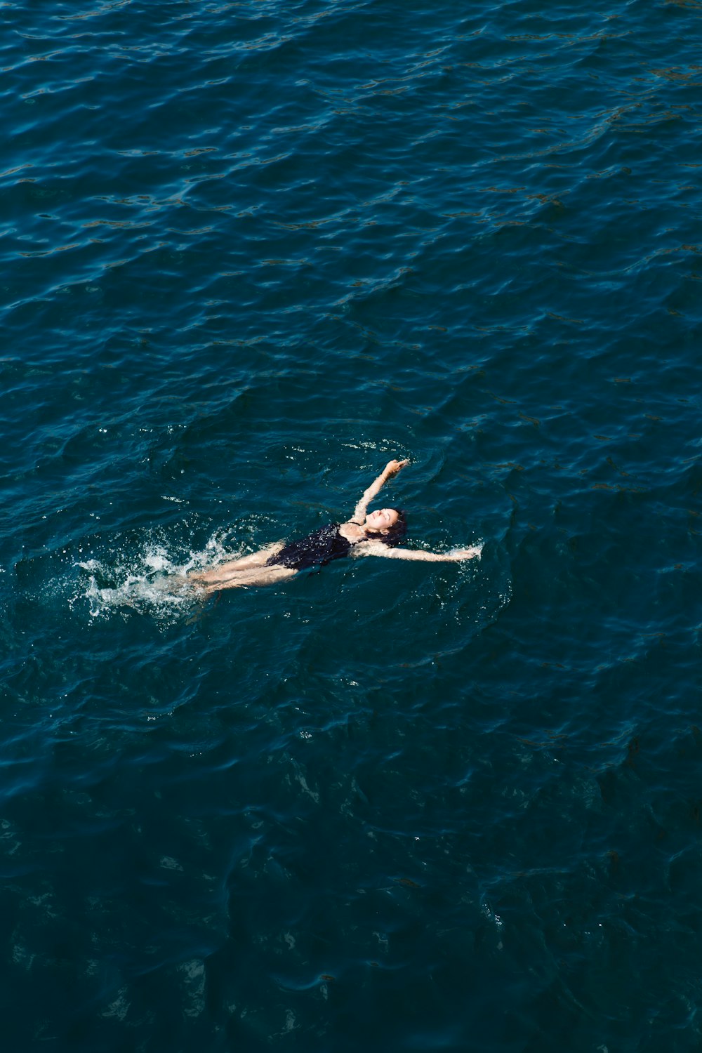 woman in black bikini swimming in blue water