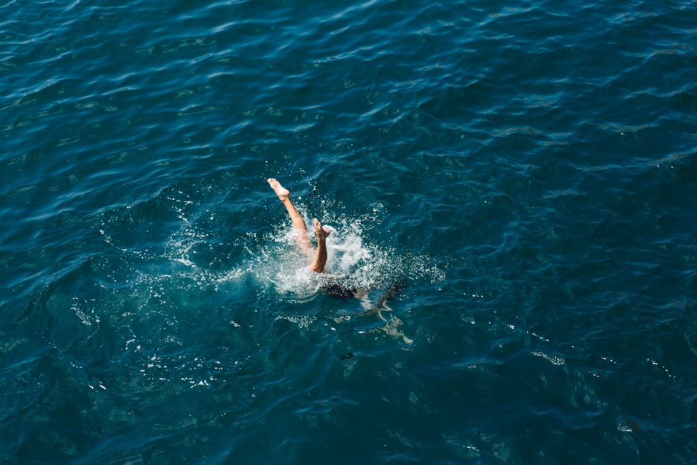 Mann in schwarzen Shorts schwimmt im blauen Wasser