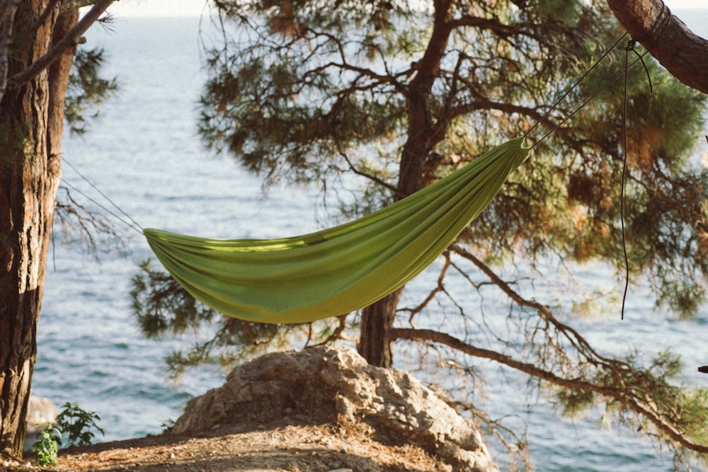 yellow and green hammock on brown rock near body of water during daytime