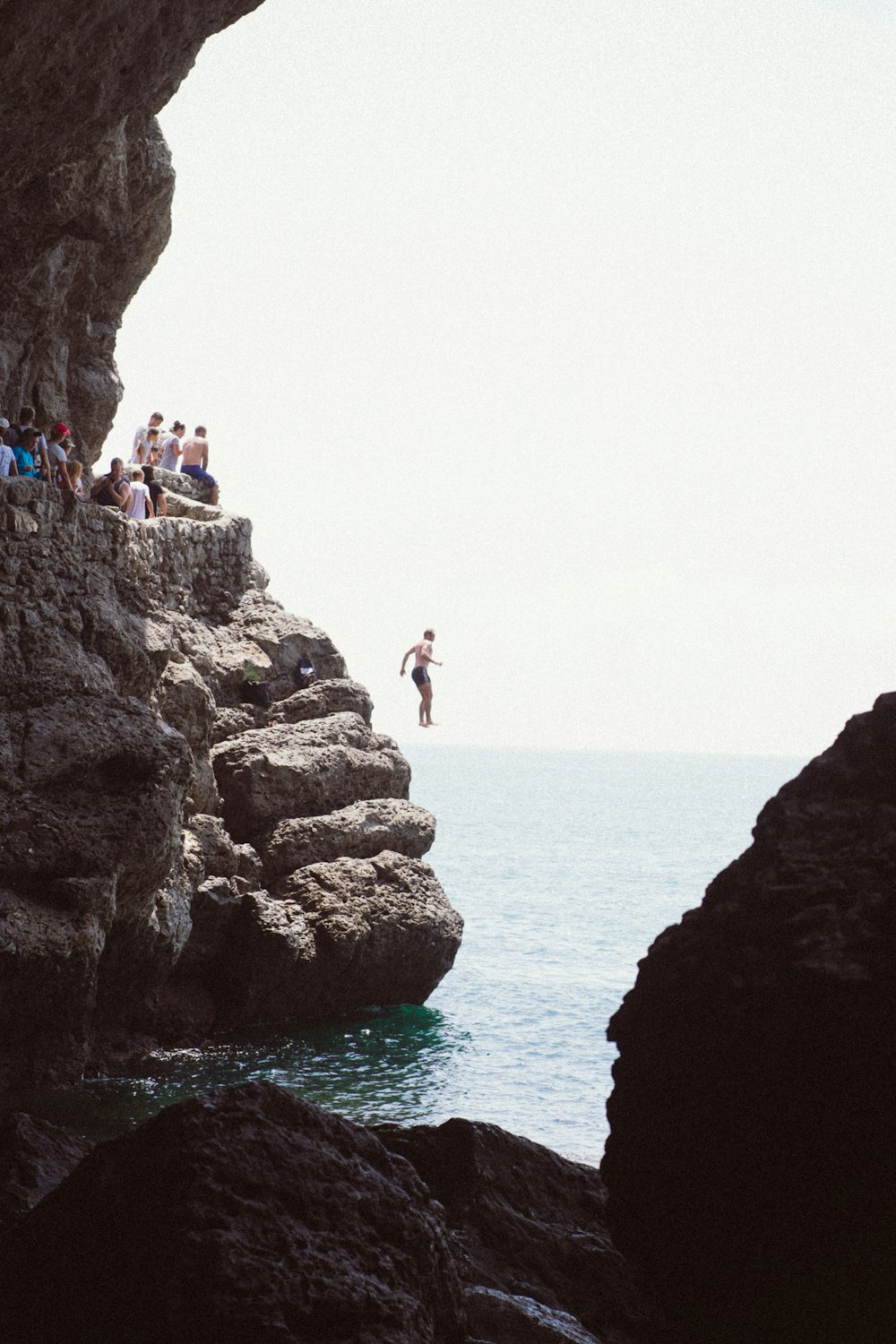 people standing on rock formation near sea during daytime