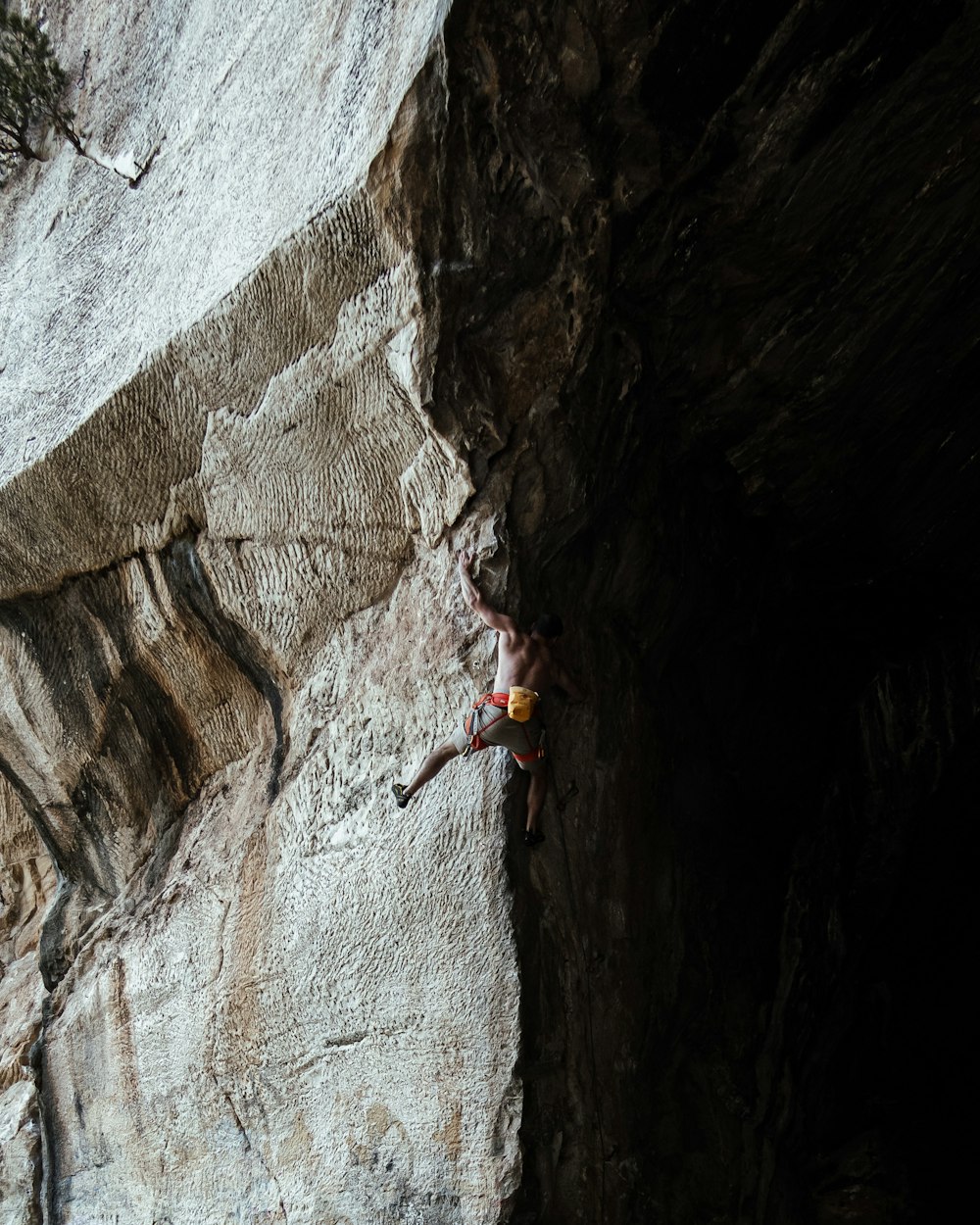 woman in red tank top climbing on brown rock