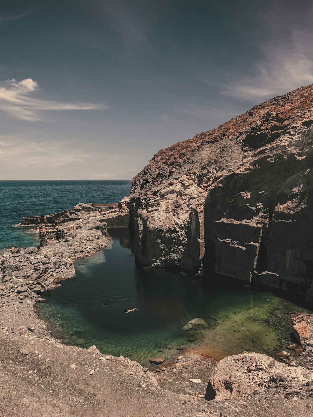 brown rock formation on sea under blue sky during daytime