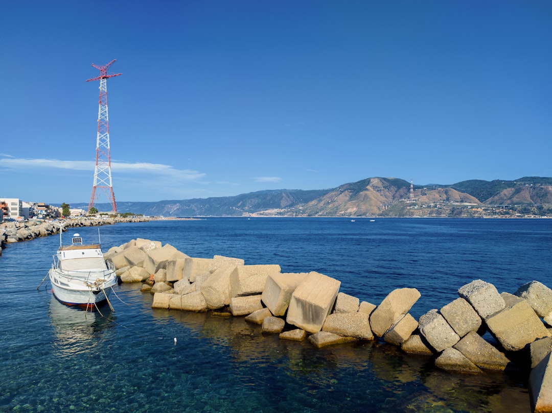 white and red windmill near body of water during daytime