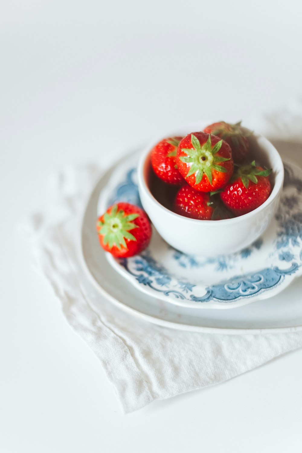 strawberry in white ceramic bowl on white table cloth