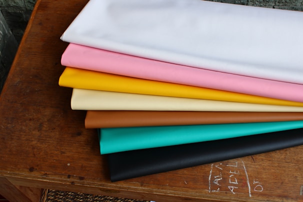 Brightly colored handmade cloth wipes neatly stacked on a rustic wooden table.
