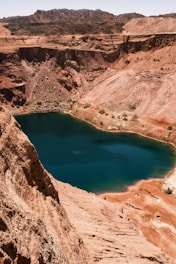 blue lake surrounded by brown rocky mountains during daytime