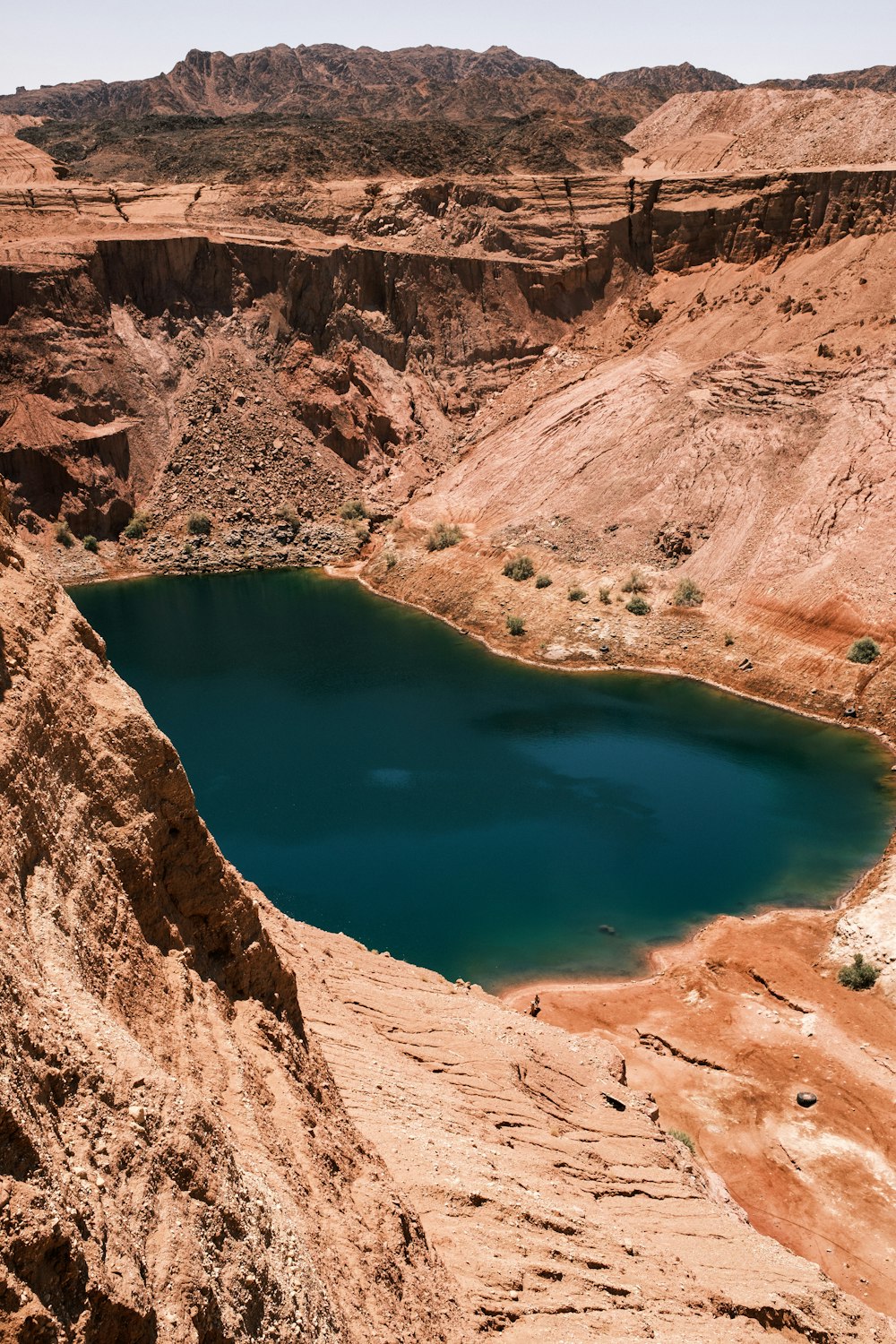 blue lake surrounded by brown rocky mountains during daytime