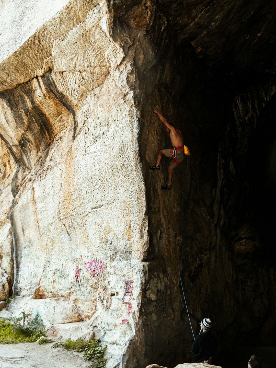 woman in black tank top climbing on brown rock formation during daytime