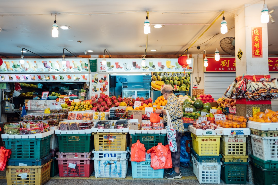 woman in yellow and white floral dress standing in front of fruit stand