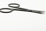 Close-up of a shiny stainless steel surgical scissors resting on a clean white surface.